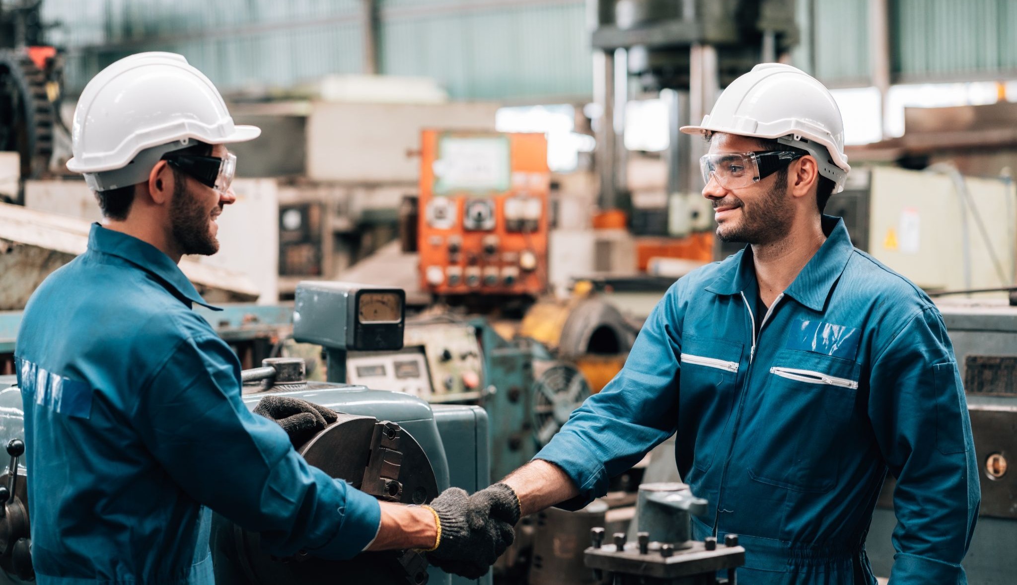 Two technicians shaking hands across in an industrial aerospace supply environment.